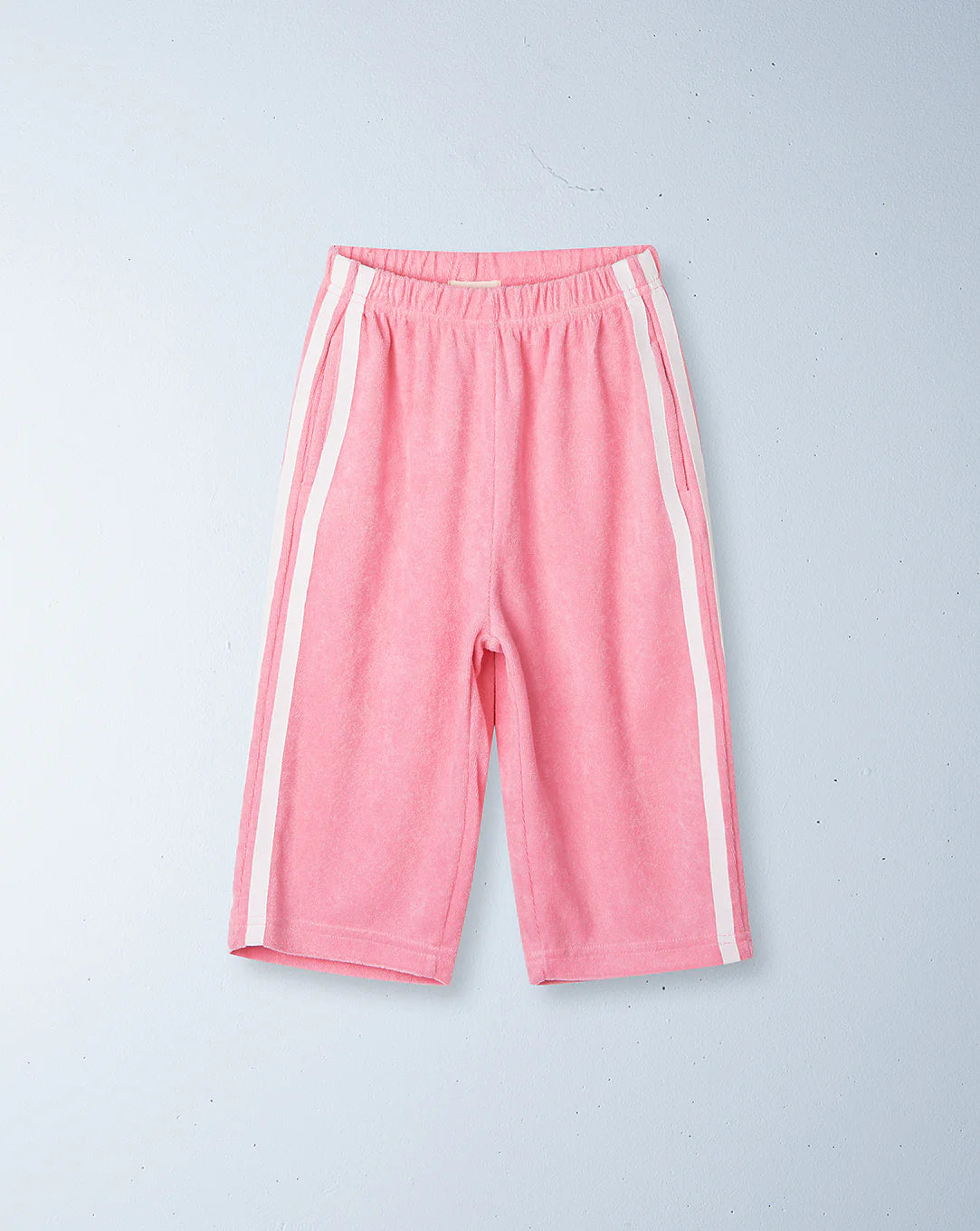 The ZIGGY ZAZA Ziggy Zaza ~ Twin Stripe Terry Pant Pink features twin white side stripes and an elastic waistband for comfort. Made from 100% terry cotton, these shorts are displayed on a light gray background.