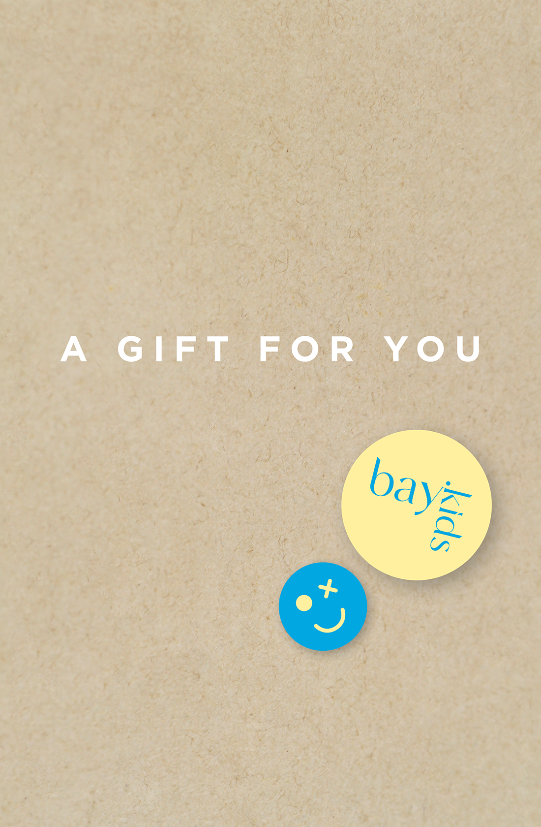 A beige background with the text "A GIFT FOR YOU" in white capital letters. Below the text are two circular stickers: one yellow with "BAY KIDS" written in blue, and the other blue with a smiley face. It's perfect for gift cards or online shopping enthusiasts, specifically featuring the Bay Kids Gift Card from BAY KIDS.