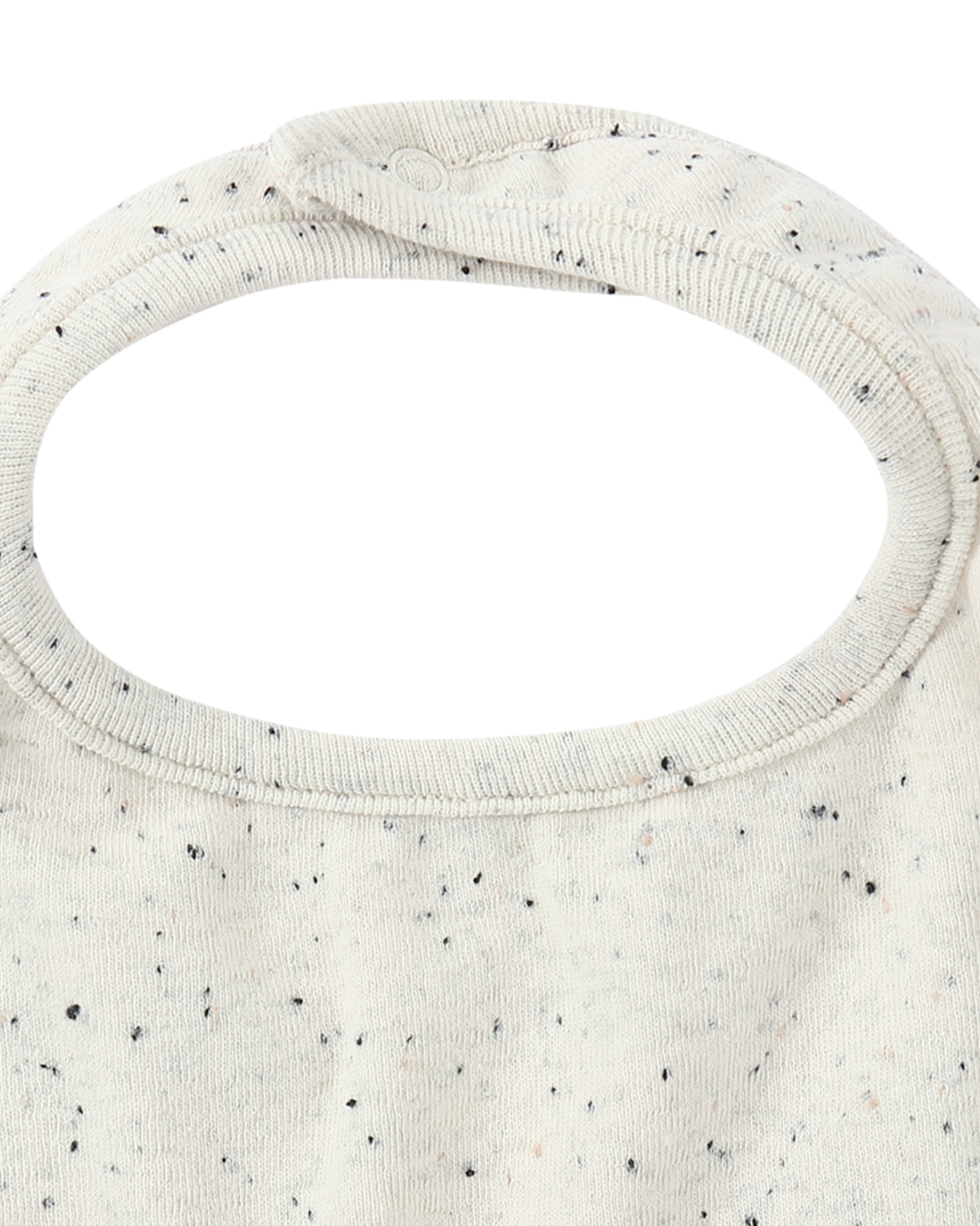 A close-up view of the Boxy Bib Quinoa Speckle by SUSUKOSHI showcases its small black speckles on a white background. The bib features a rounded neckline and a snap button closure at the top. Made from soft organic cotton, it provides ultimate comfort for infants.