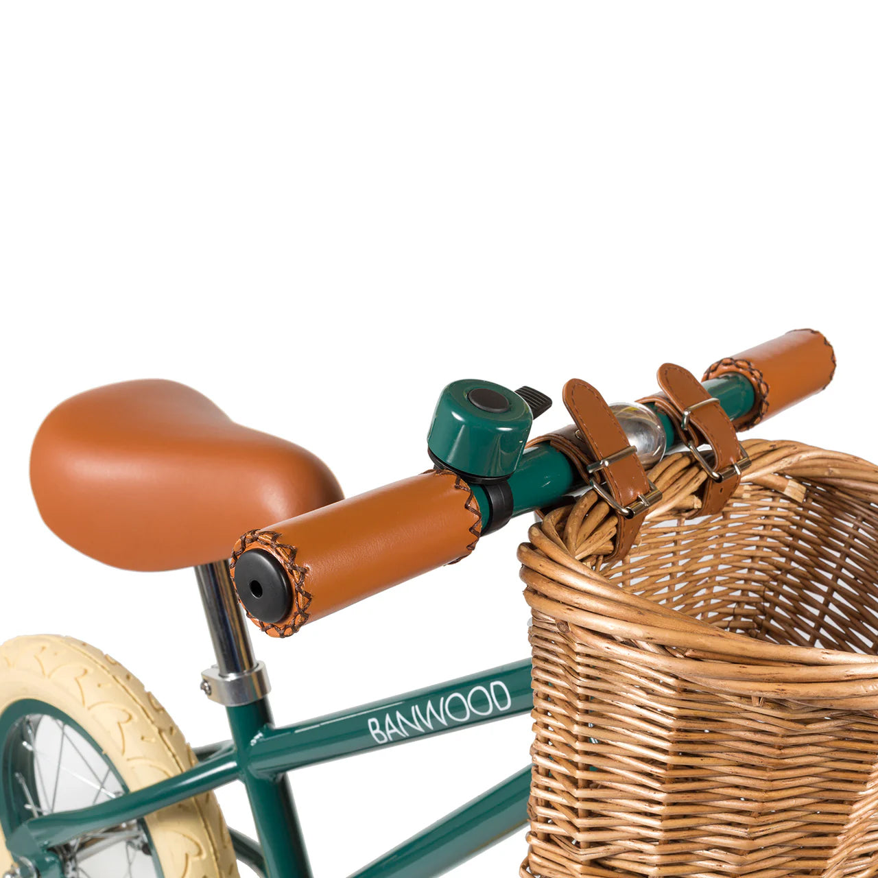 A close up of a dark green and black bike bell on the handle of a dark green banwood vintage balance bike with a straw basket.