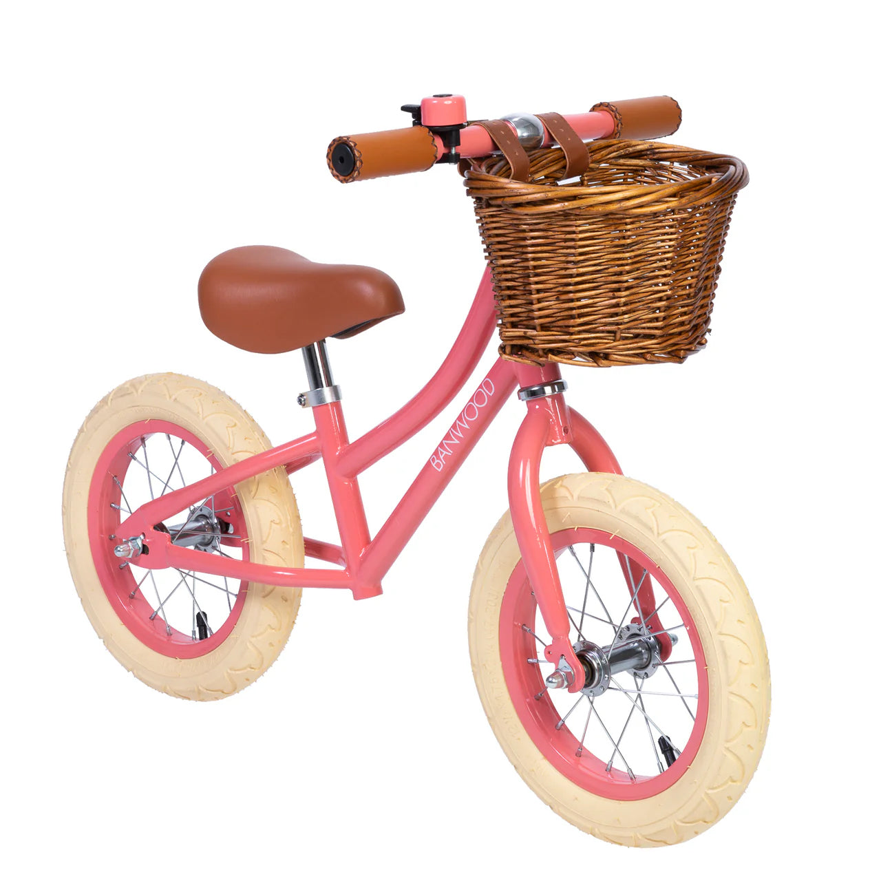 A 45 degree angle shot of a coral banwood vintage balance bike with a straw basket.