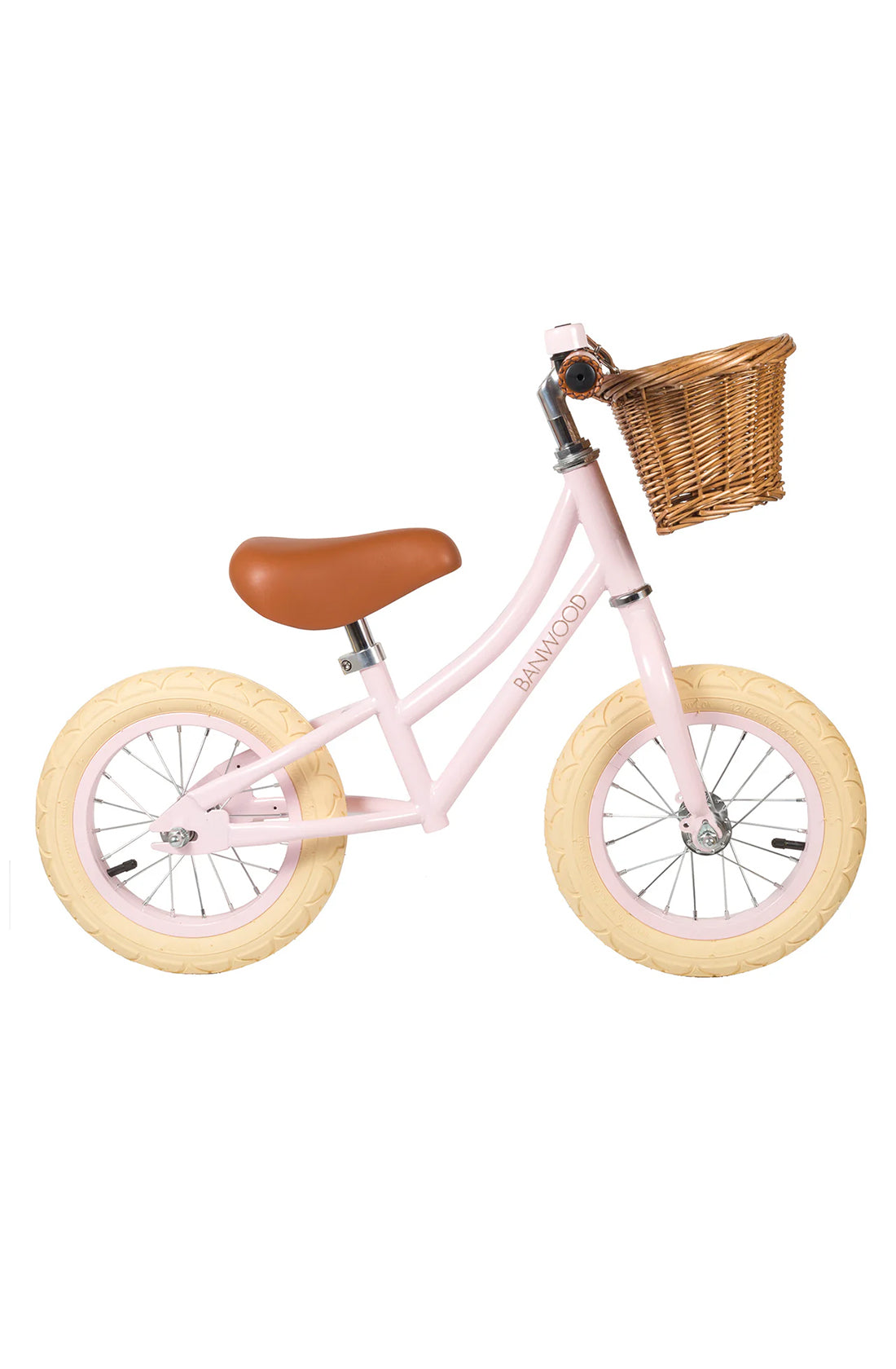 A side on shot of a pink banwood vintage balance bike with a straw basket.