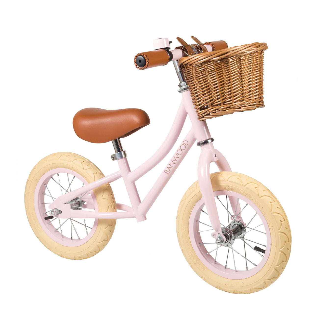 A 45 degree angle shot of a pink banwood vintage balance bike with a straw basket.