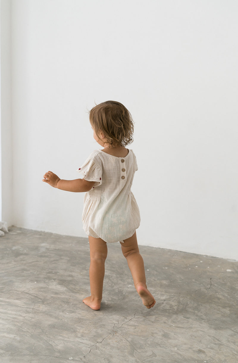 Rear view of toddler girl wearing romper showing the coconut buttons at the back neckline.