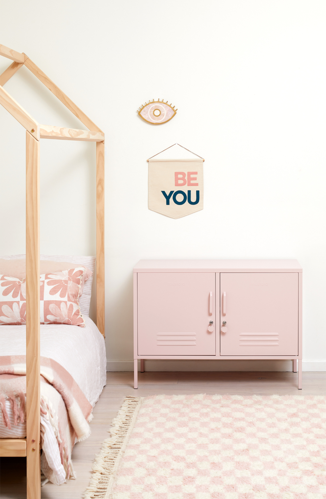 The lowdown locker in blush next to a bed.