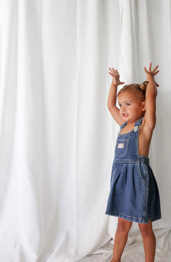 Girl with arms in the air wearing denim dress with nothing underneath