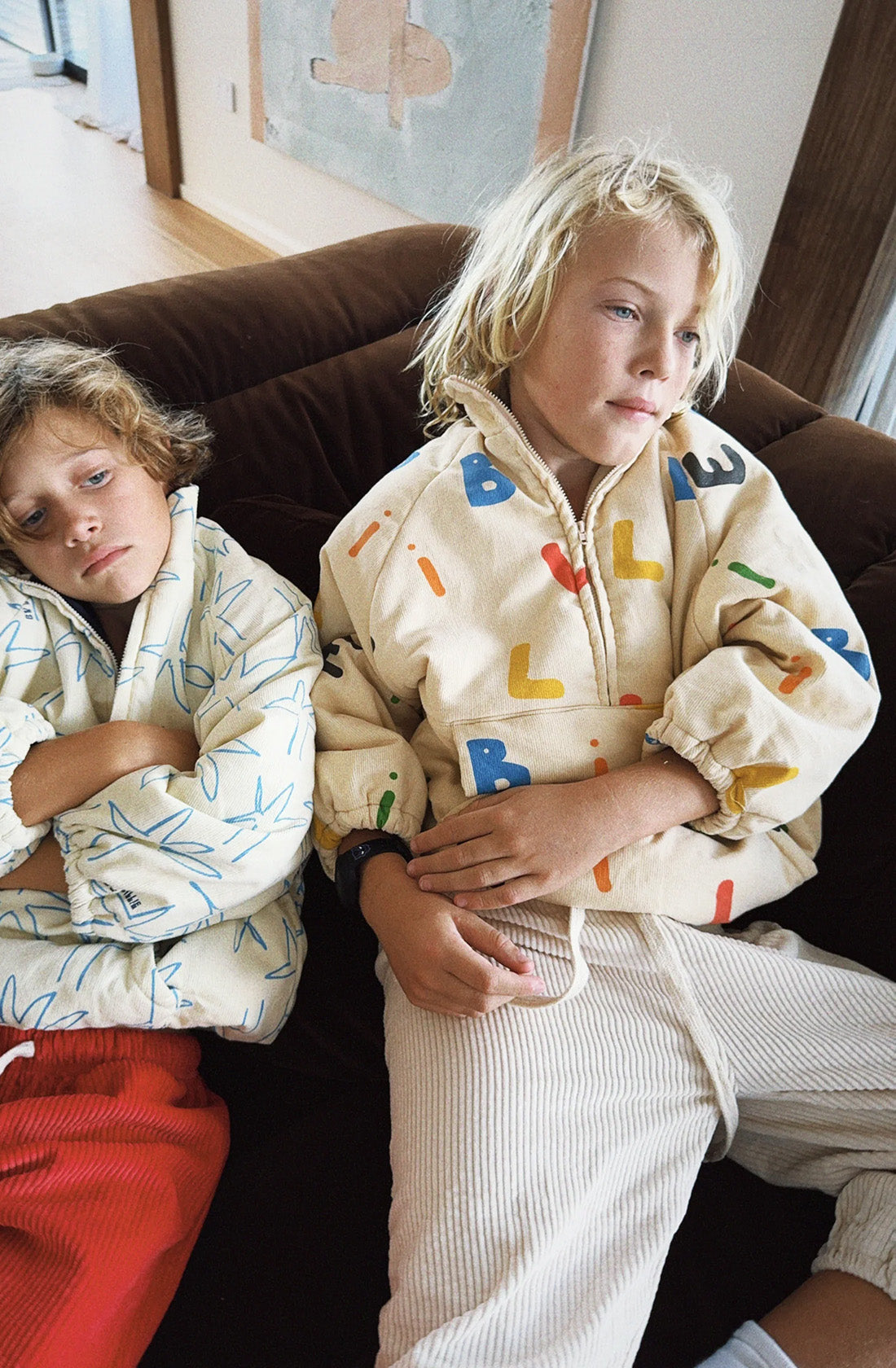 Boy wearing the alphabet Joey jacket sitting on a couch.