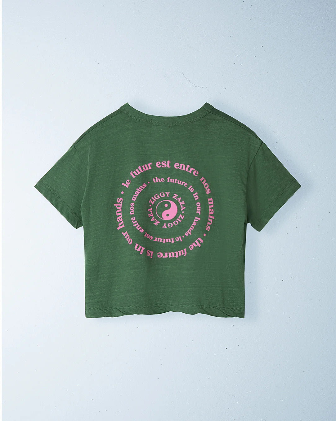 The Ziggy Zaza ~ Love Your Mother Tee Lizard by ZIGGY ZAZA is a green, relaxed boxy-fit T-shirt made from lightweight washed cotton. It features a round pink graphic with an eye on the back, encircled by "LE FUTUR EST ENTRE NOS MAINS" and "THE FUTURE IS IN OUR HANDS.