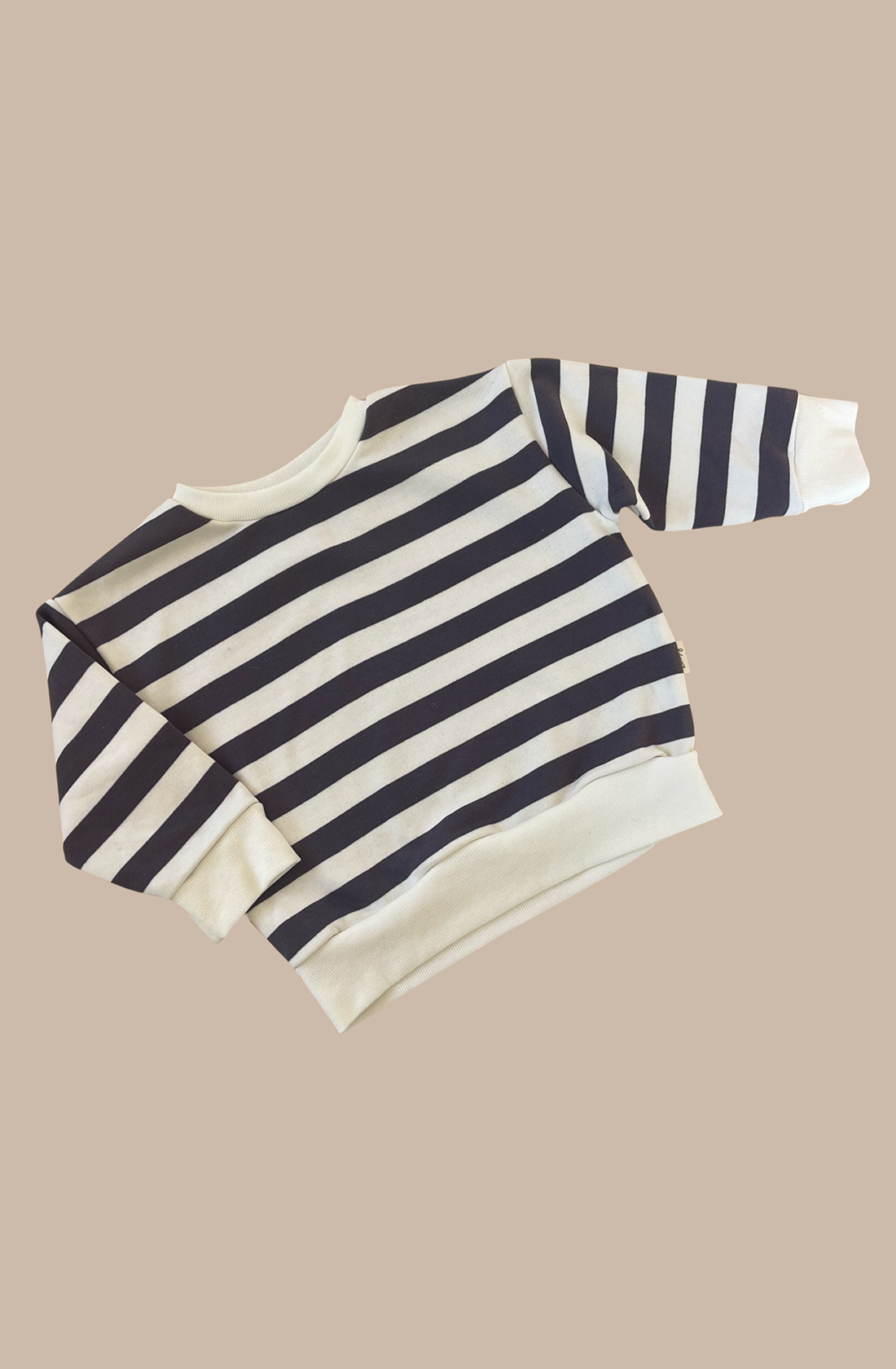 The Camden navy striped pullover on a light brown background.