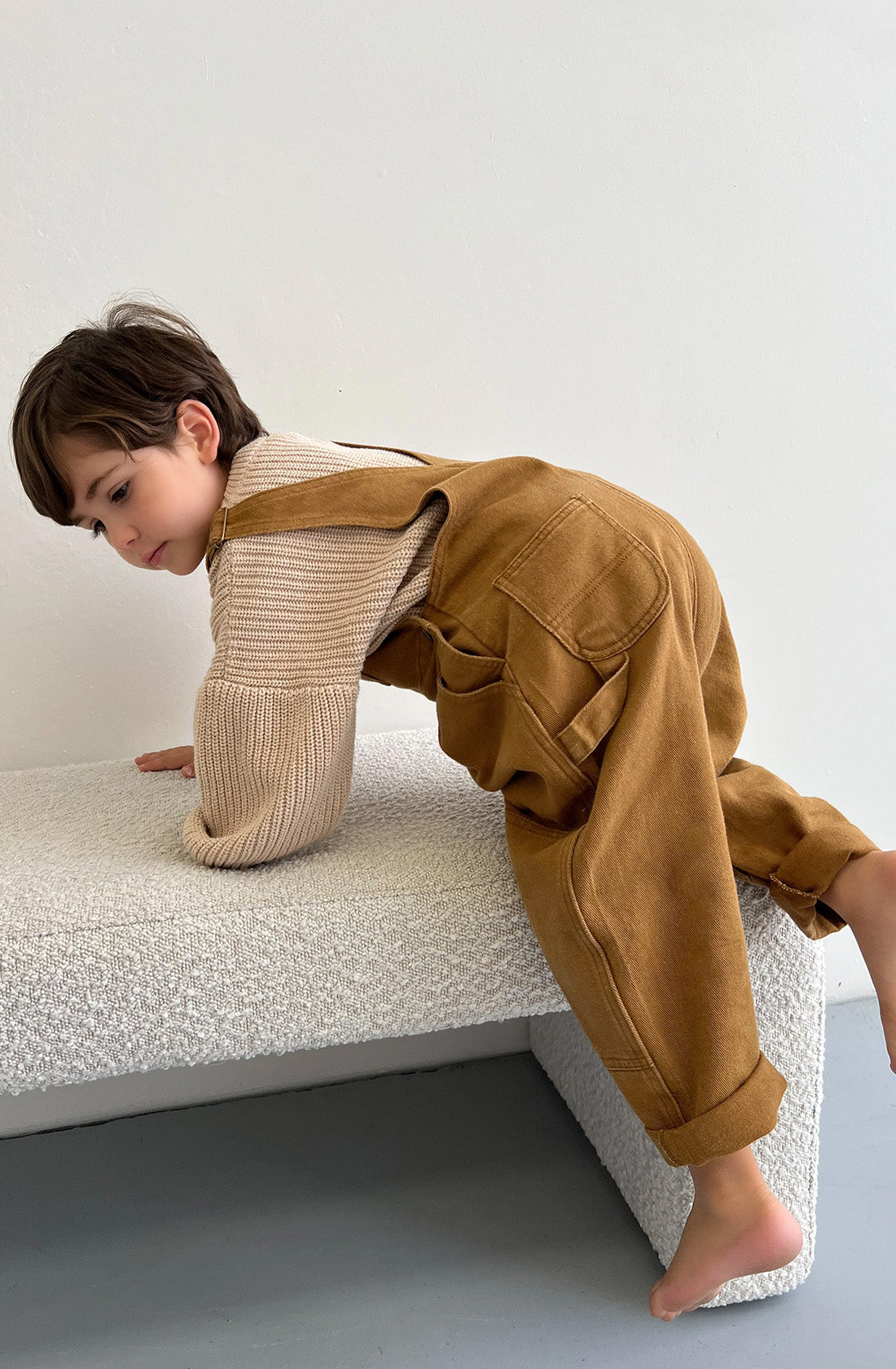 Boy climbing onto bench wearing the Carpenter overalls