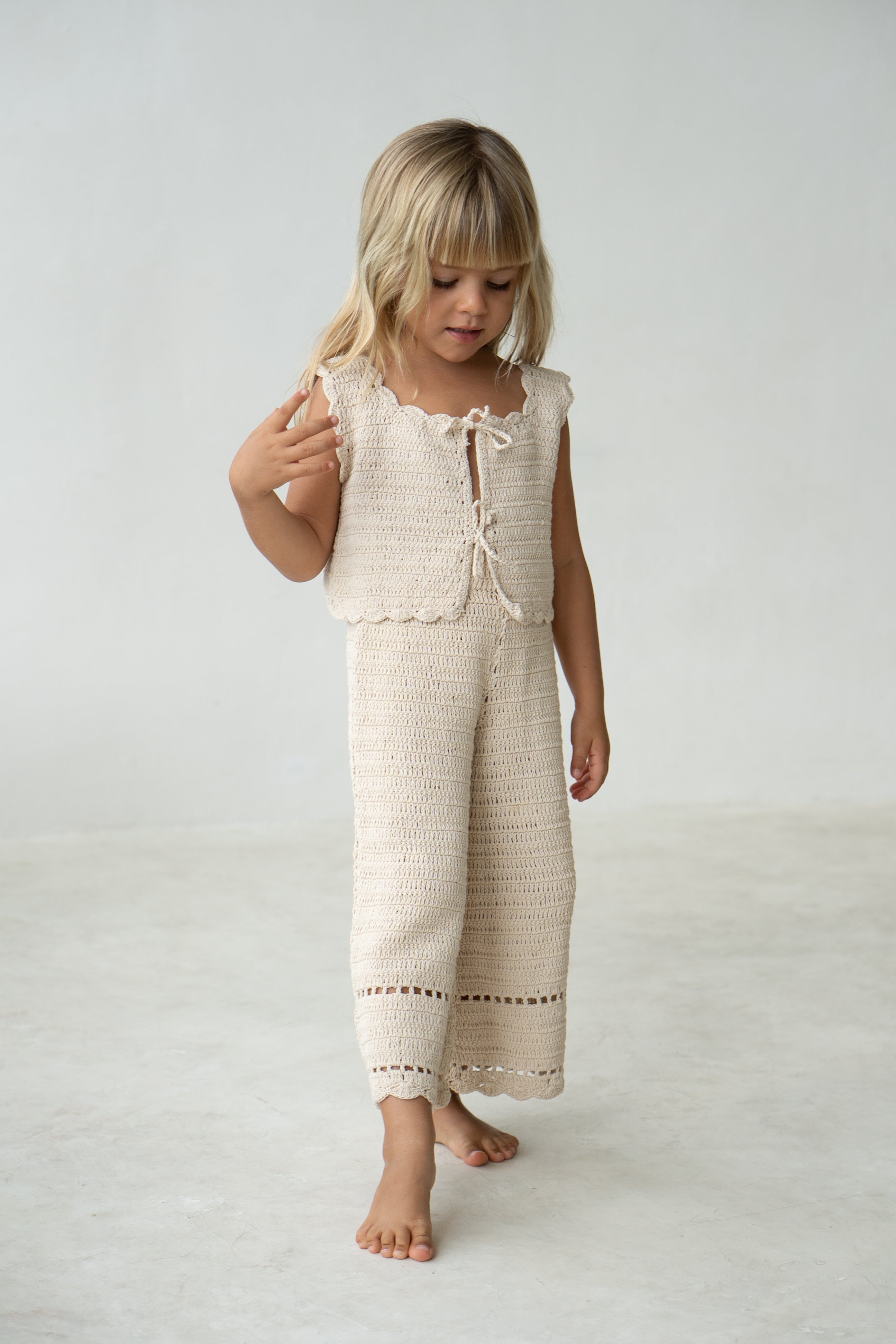 Young girl wearing the crochet pant in ecru with matching vest.