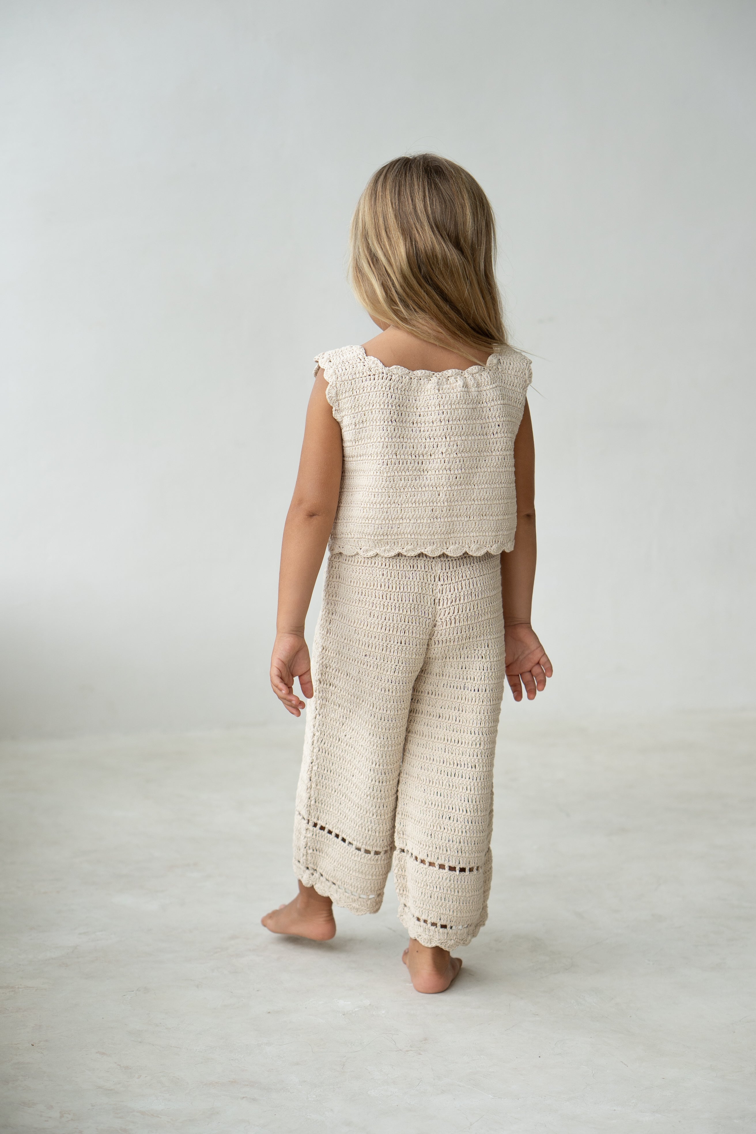 Young girl wearing the crochet pant in ecru with matching vest.