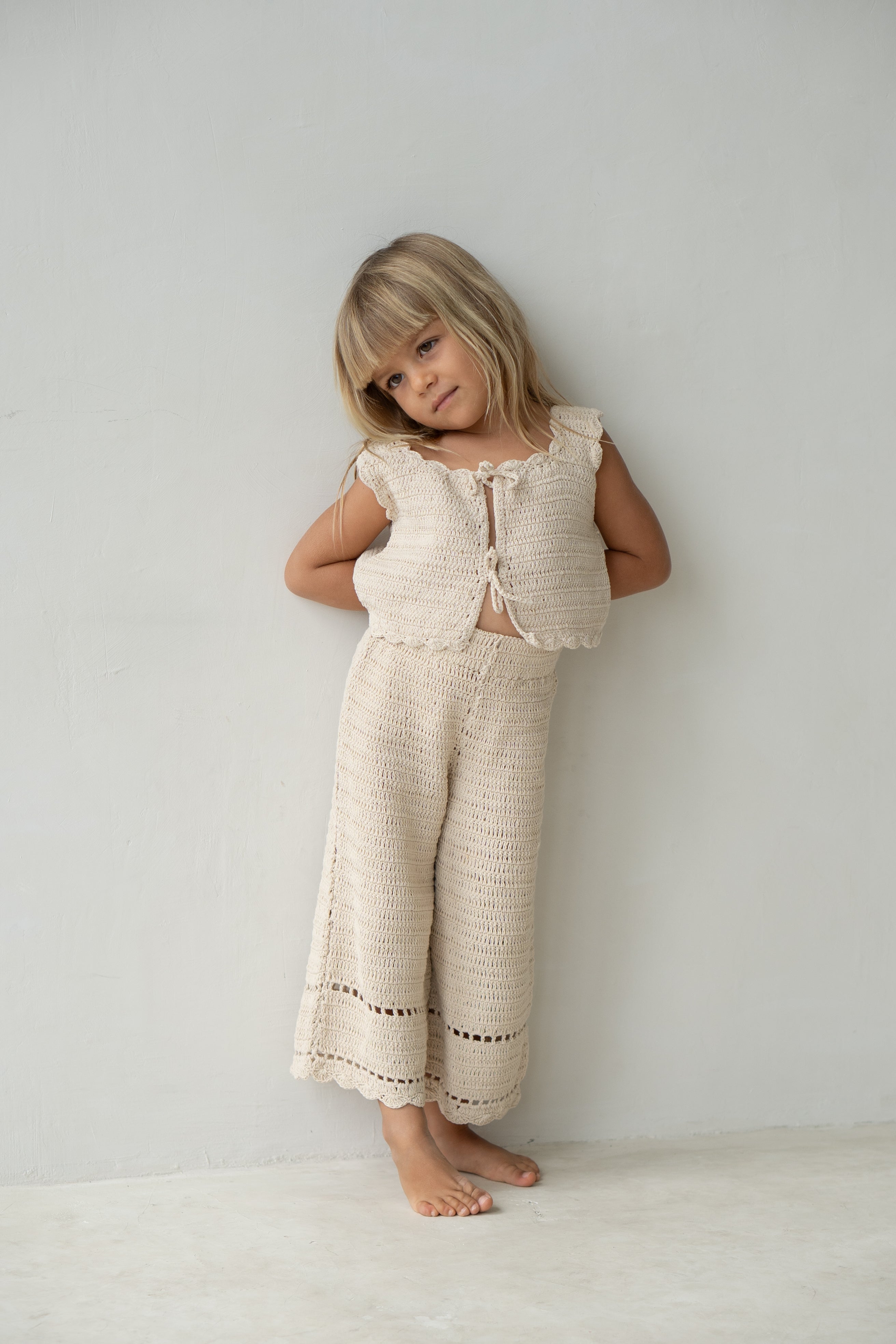 Young girl wearing the crochet pant in ecru with matching vest.