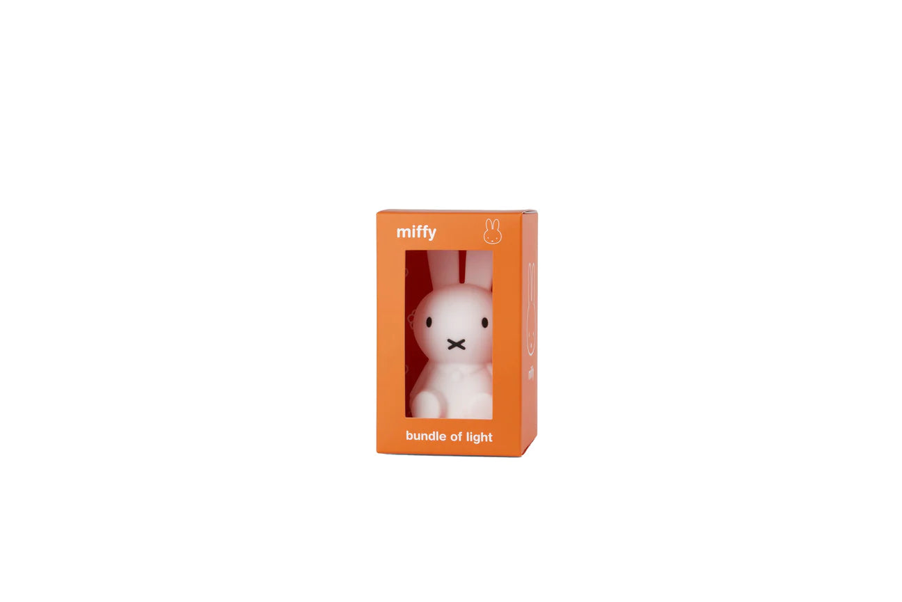 The Bundle of Light - Miffy by MR MARIA is a charming collectable mini-light packaged in an orange box with a clear window. The box features the text "miffy" at the top and "bundle of light" at the bottom. This small, soft silicone LED lamp is shaped like a white bunny and boasts a simple, minimalist design.