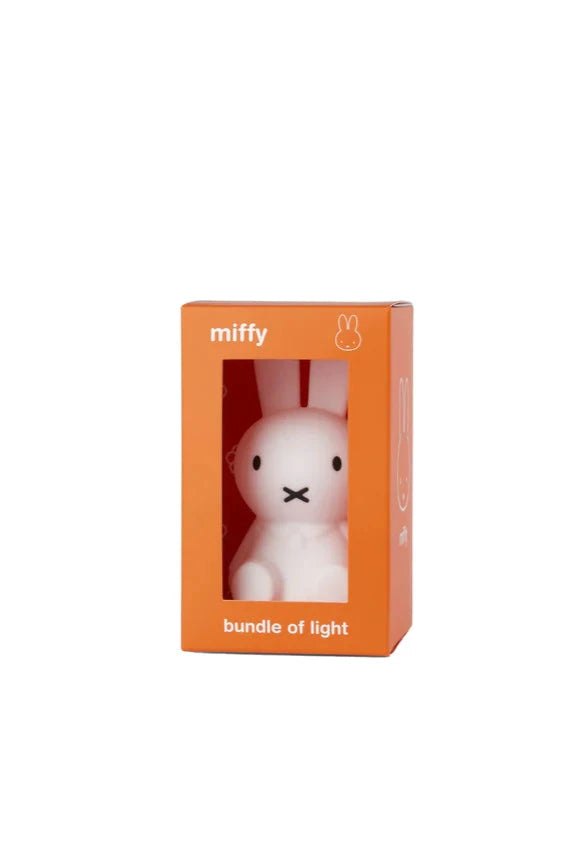 The Bundle of Light - Miffy by MR MARIA is a charming collectable mini-light packaged in an orange box with a clear window. The box features the text "miffy" at the top and "bundle of light" at the bottom. This small, soft silicone LED lamp is shaped like a white bunny and boasts a simple, minimalist design.