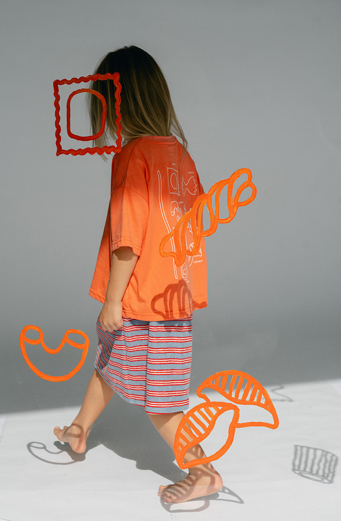 A young kid wearing the Lenn Peppa skirt with orange top..