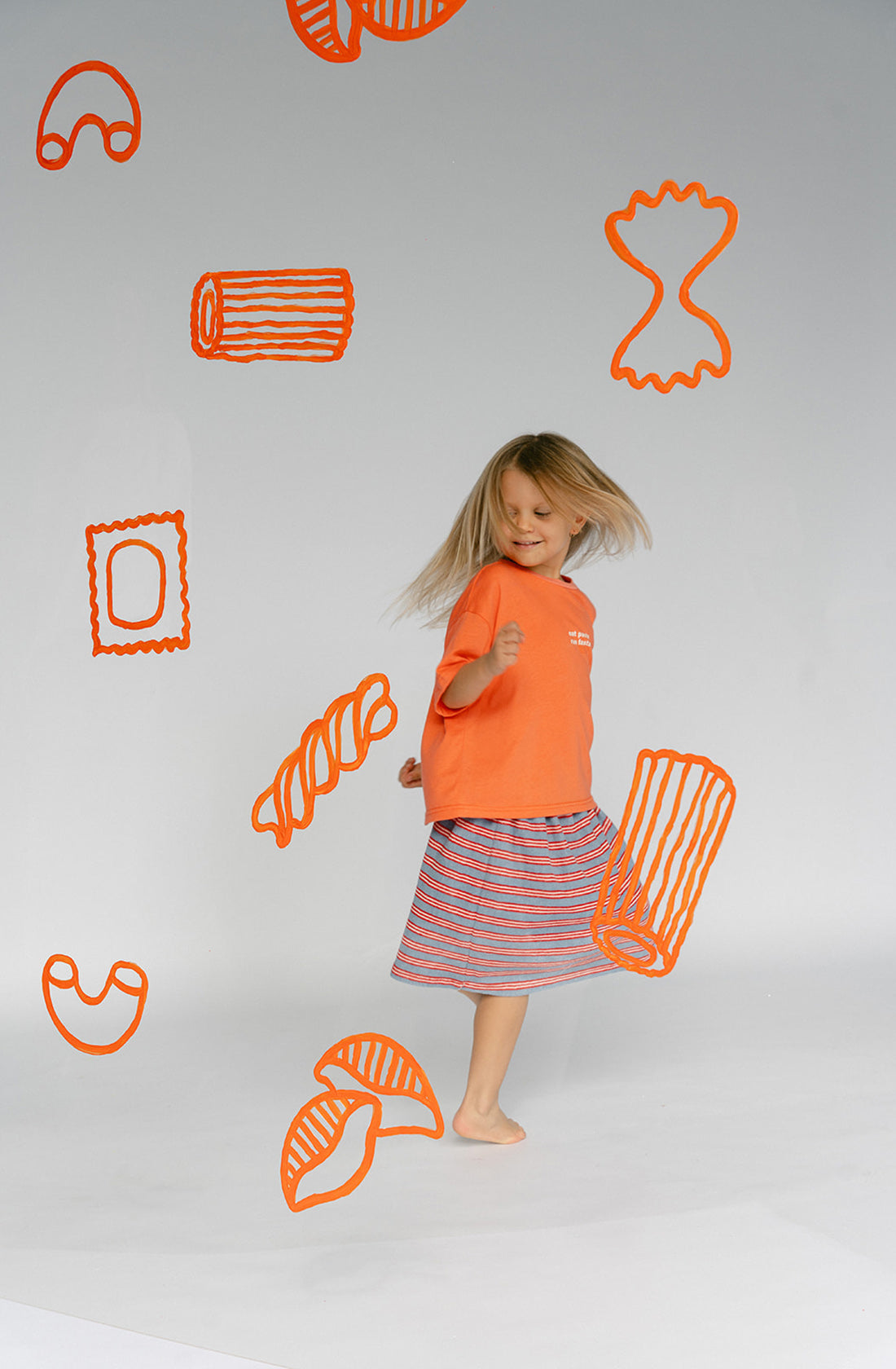 A young kid wearing the Lenn Peppa skirt with orange top twirling around..