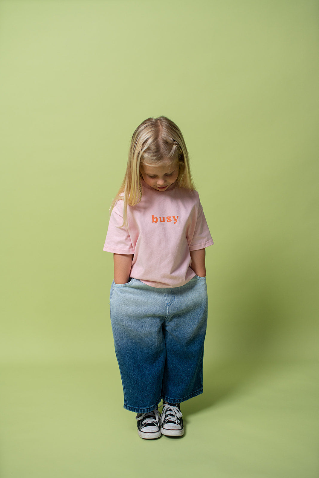 A young kid wearing the Lenn busy tee sunset shirt in pink.