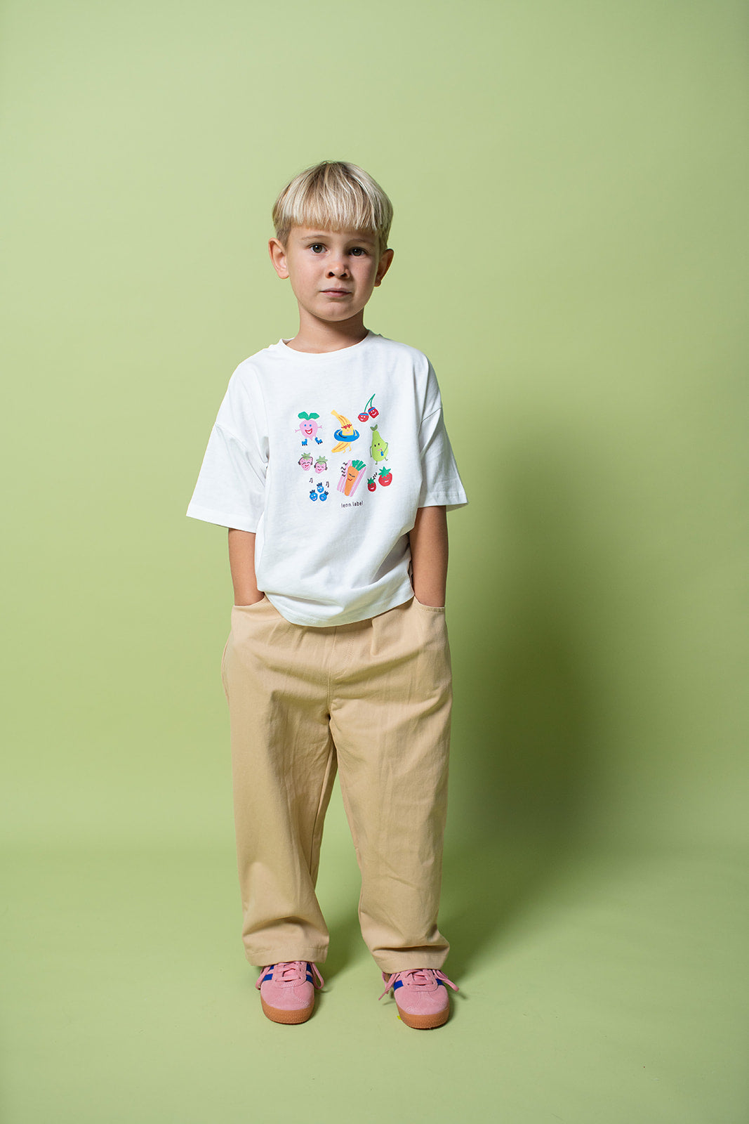 A young kid wearing the Lenn snack tee in white with blue jeans.