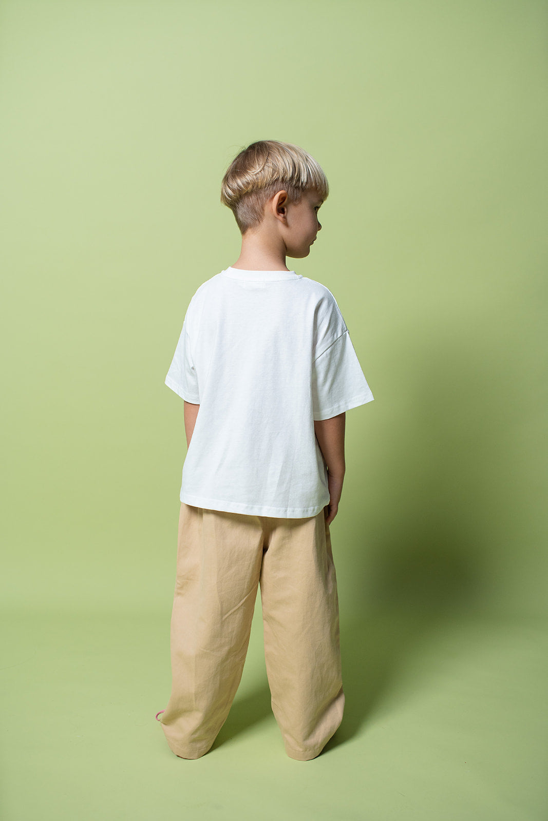 A young kid wearing the Lenn snack tee in white from the back.