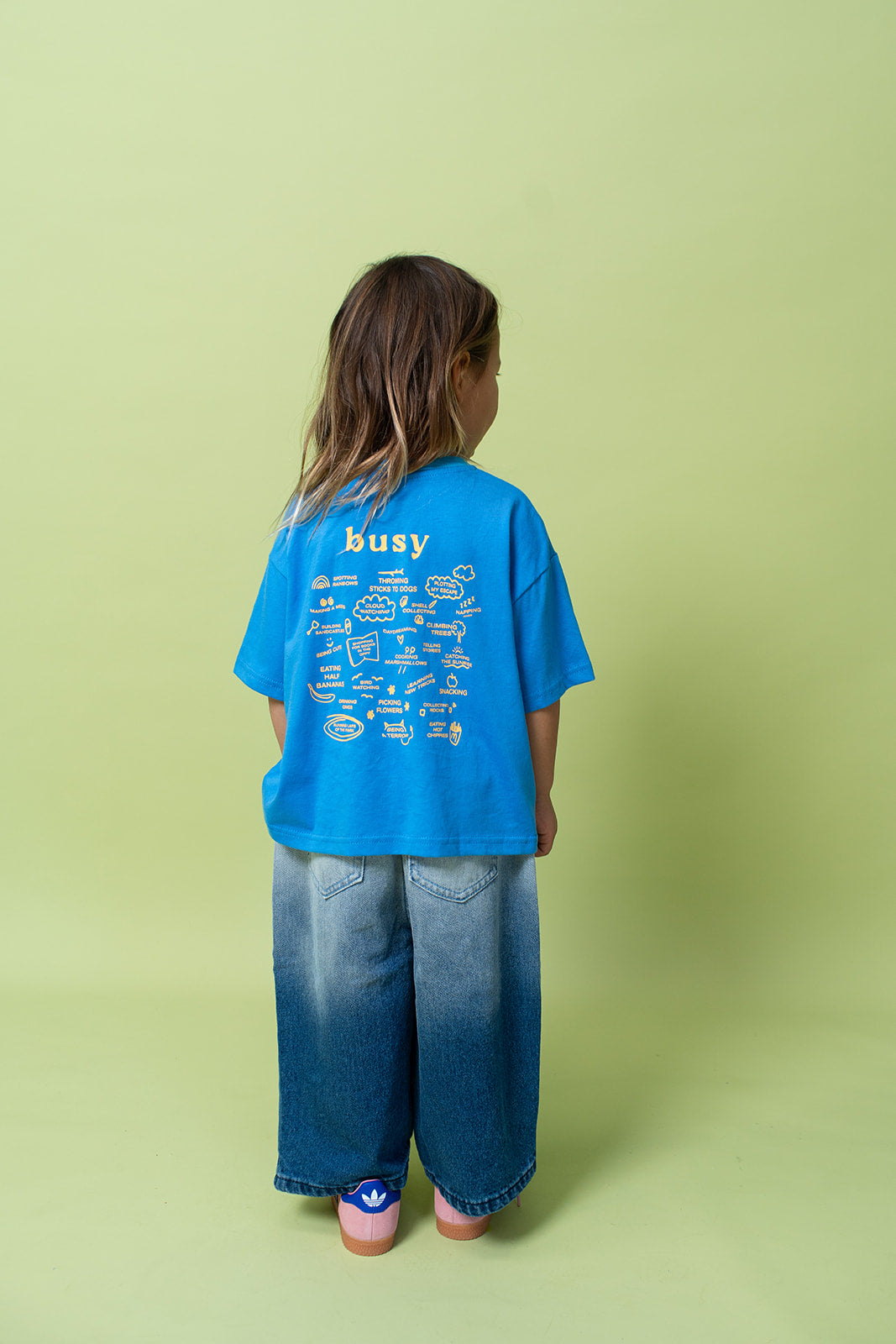 A young kid wearing the Lenn busy tee sunny shirt in blue from the back.