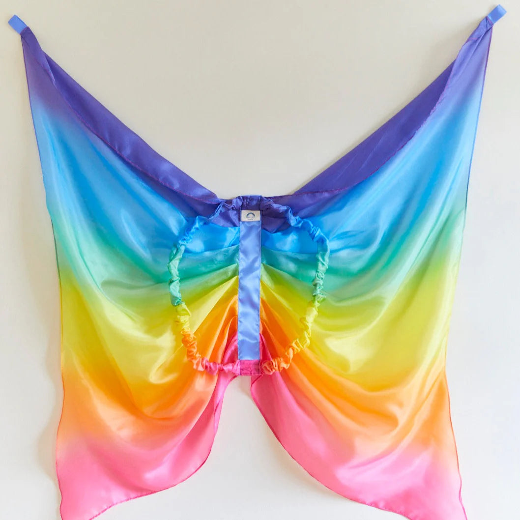 The Rainbow Wings from SARAH'S SILKS feature vibrant butterfly wings with a stunning gradient from purple to pink. Ideal for dress-up, they include an elastic band for convenient wear and are showcased against a simple light background.