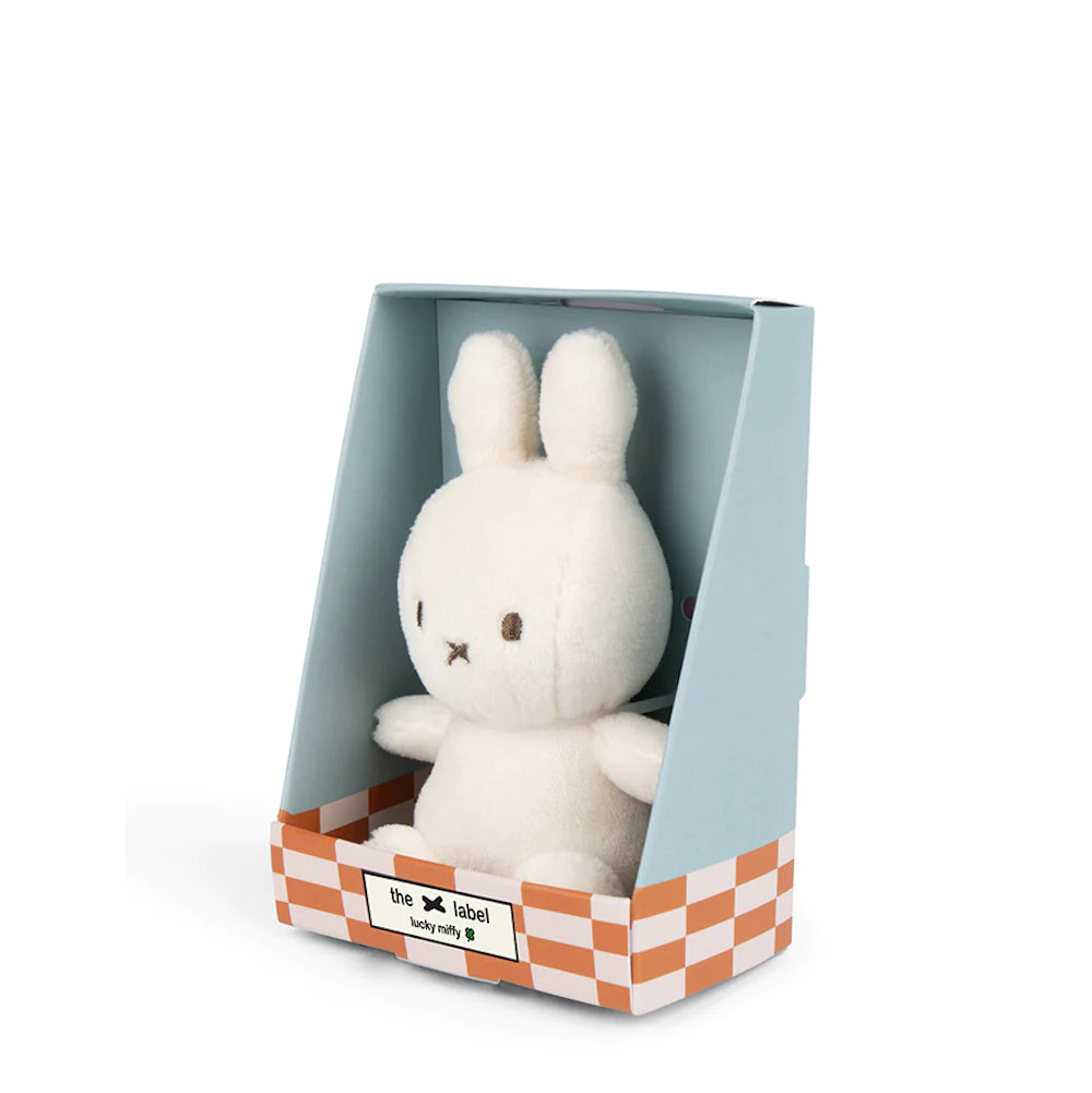 The Lucky Miffy toy, handcrafted from recycled polyester by BON TON TOYS X MIFFY, comes nestled in light blue packaging. The gift box features a checkered pattern at the base with "the label" text on it. This cream-colored rabbit, with its minimalist facial features and long ears, exudes a hint of luck.