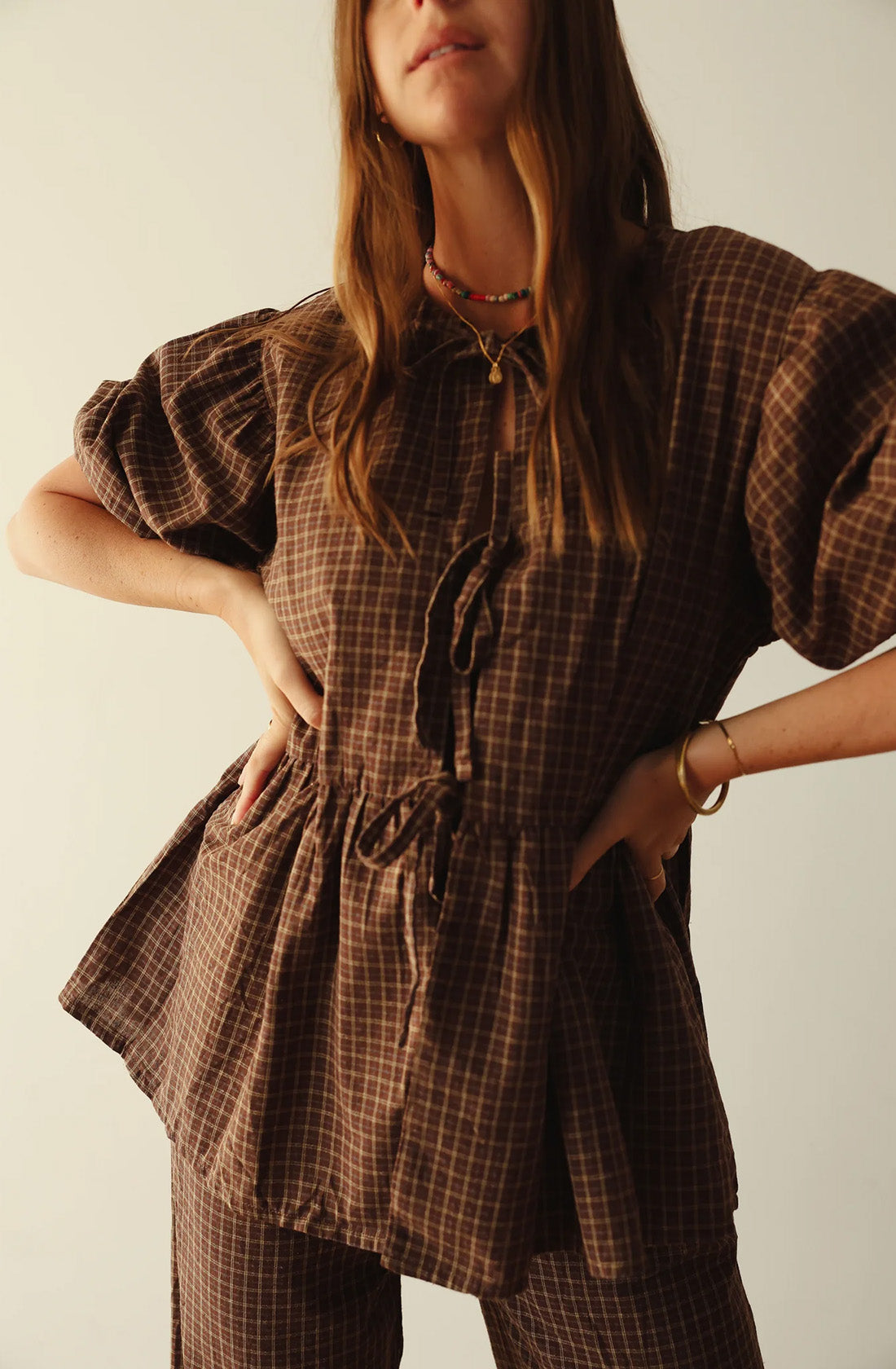 A women wearing the mama cami blouse and matching pant with her hands on her hips.