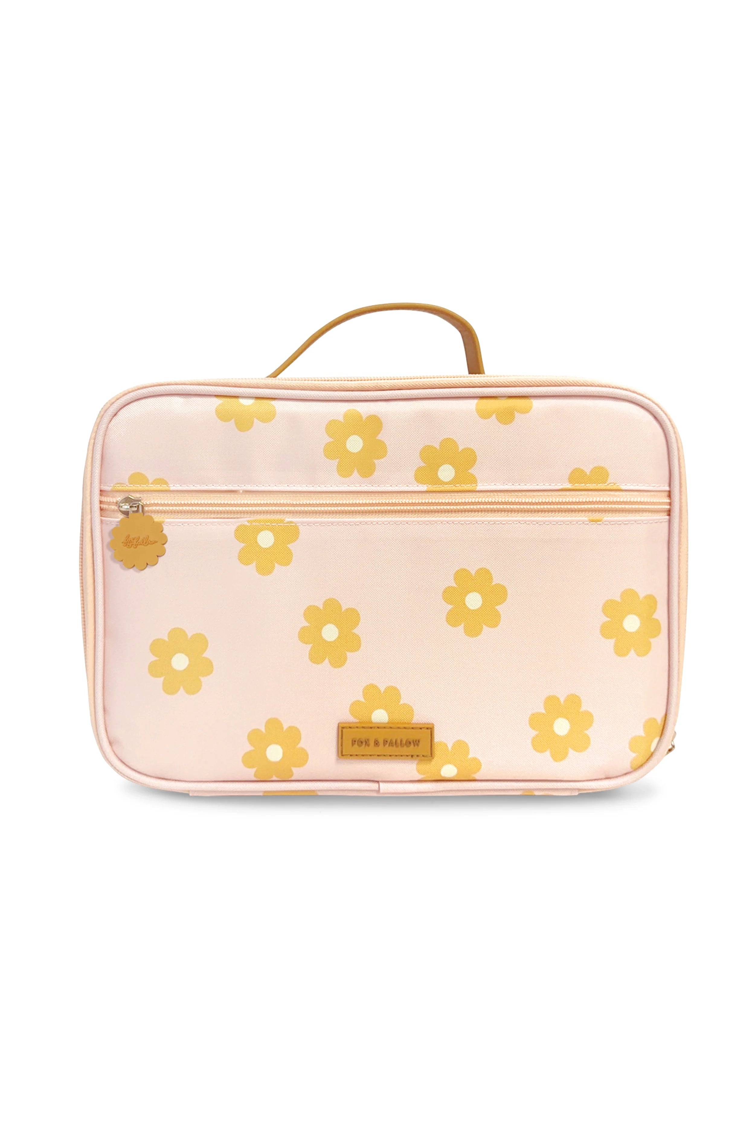 The Daisy Chain Lunch Bag by FOX & FALLOW is a light pink rectangular bag with a top handle. It features a pattern of yellow flowers and is made from waterproof fabric. The design includes a front zipper pocket and an embossed logo label at the bottom center.