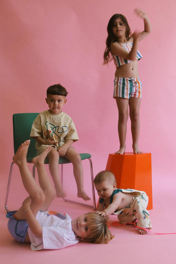 Group of kids playing on set of a photoshoot. Girl is wearing the stripe shorts with matching crop.