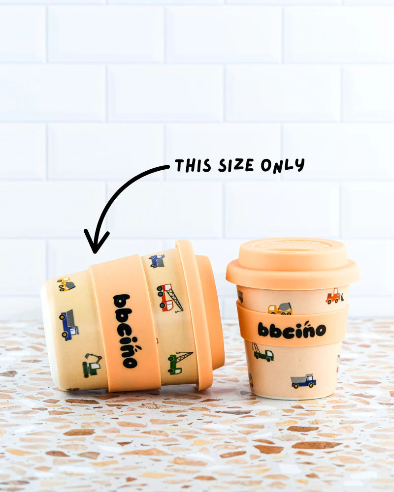 Two Reusable BambinoCino Cups (240ml) from BBCINO are displayed against a white tiled background. Crafted from sustainably farmed bamboo, these cups feature colorful vehicle designs. One cup is shown stacked on its side with an arrow pointing to it and the words "THIS SIZE ONLY." Both cups have the brand name "BBCINO" printed on them.