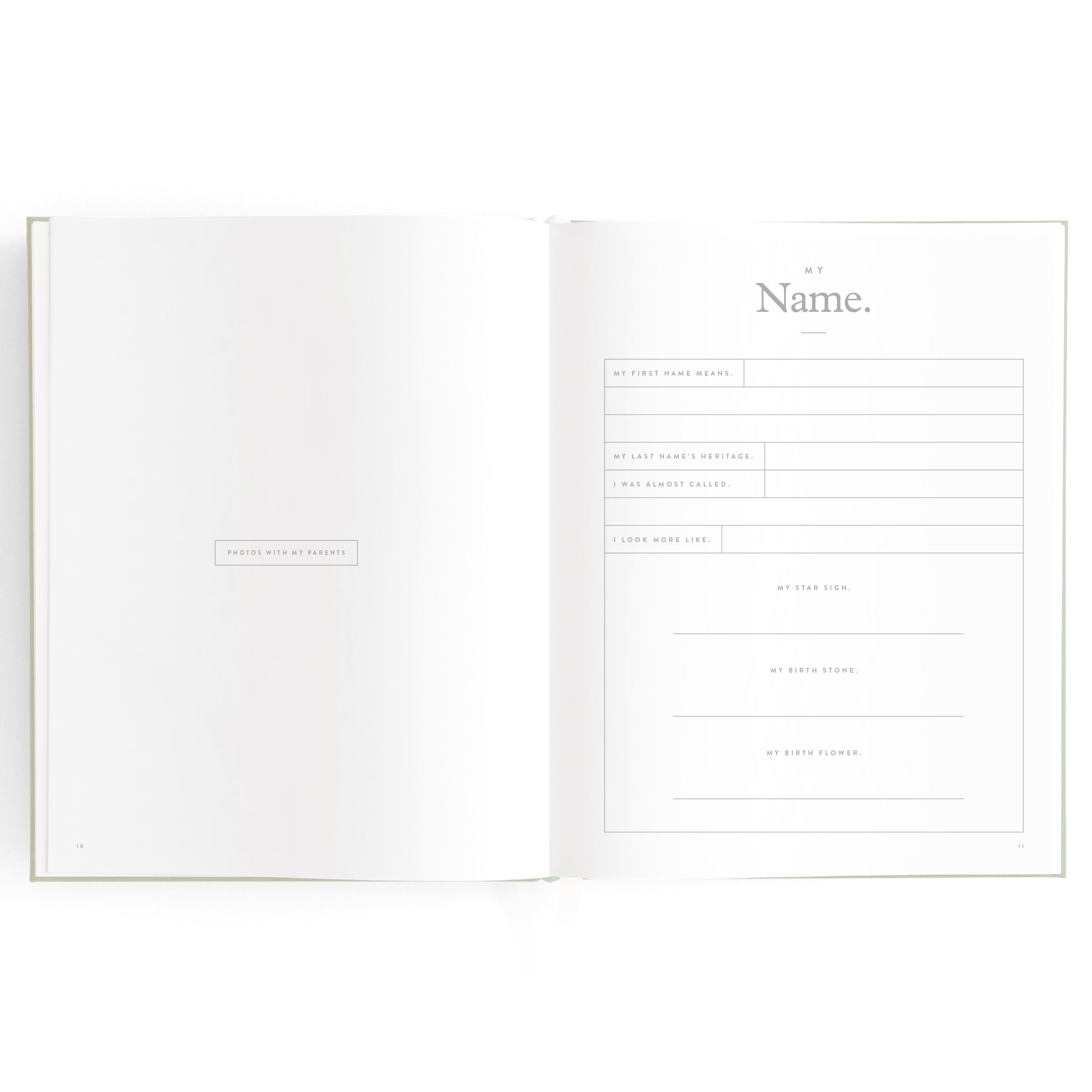 An open Baby Book Pistachio by FOX & FALLOW with two pages visible. The left page is largely empty, featuring a small rectangle in the center containing the text, "PAPER DESIGN & DIRECTION." The right page, ideal for a memory album or family keepsake, is titled "My Name." and includes lined sections for writing personal information.