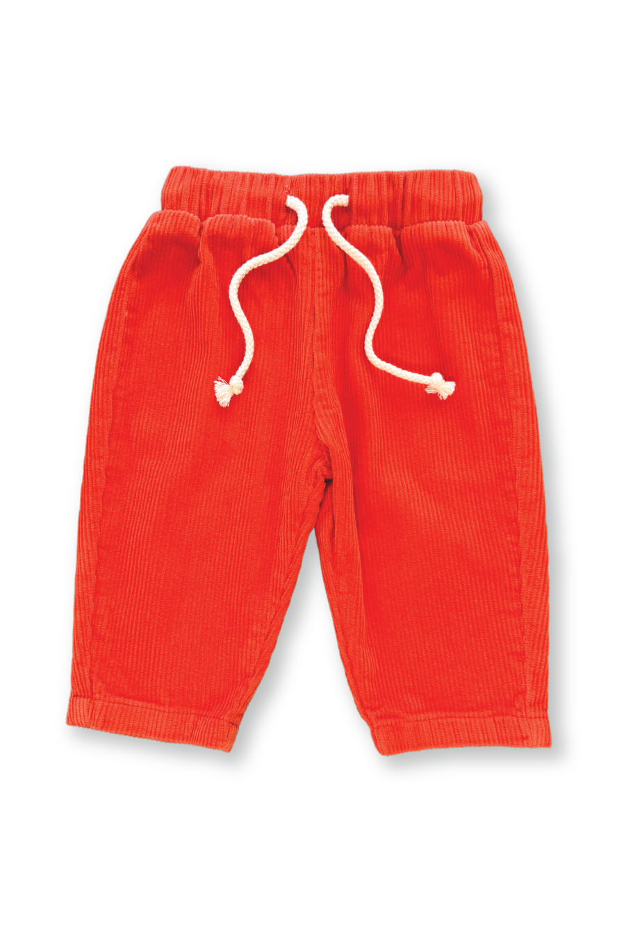 The GROWN ~ Organic Cord Pant in Tomato features a bright orange, corduroy-like texture made from organic cotton, complete with an elastic waistband and white drawstrings. Displayed flat against a white background.