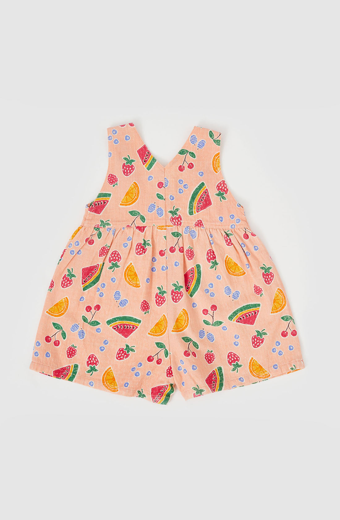 The Sara Linen Shortalls from GOLDIE + ACE are pink, sleeveless baby rompers adorned with a charming hand-drawn fruit print featuring watermelons, oranges, strawberries, and blueberries. Crafted from a linen/cotton blend, they boast a V-shaped back and gathered waist for a playful look. Adjustable button straps ensure the perfect fit.