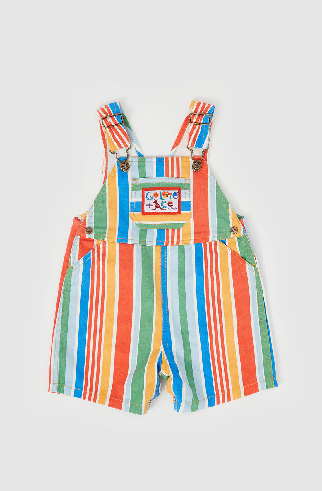 The Burton Striped Denim Overalls by GOLDIE + ACE are vibrant toddler dungarees featuring vertical red, green, yellow, and blue stripes. They come with adjustable shoulder straps secured by buttons and an embroidered chest pocket adorned with a design of four buildings and the word "Care." For convenience, there are snaps on the legs to make changing easy.