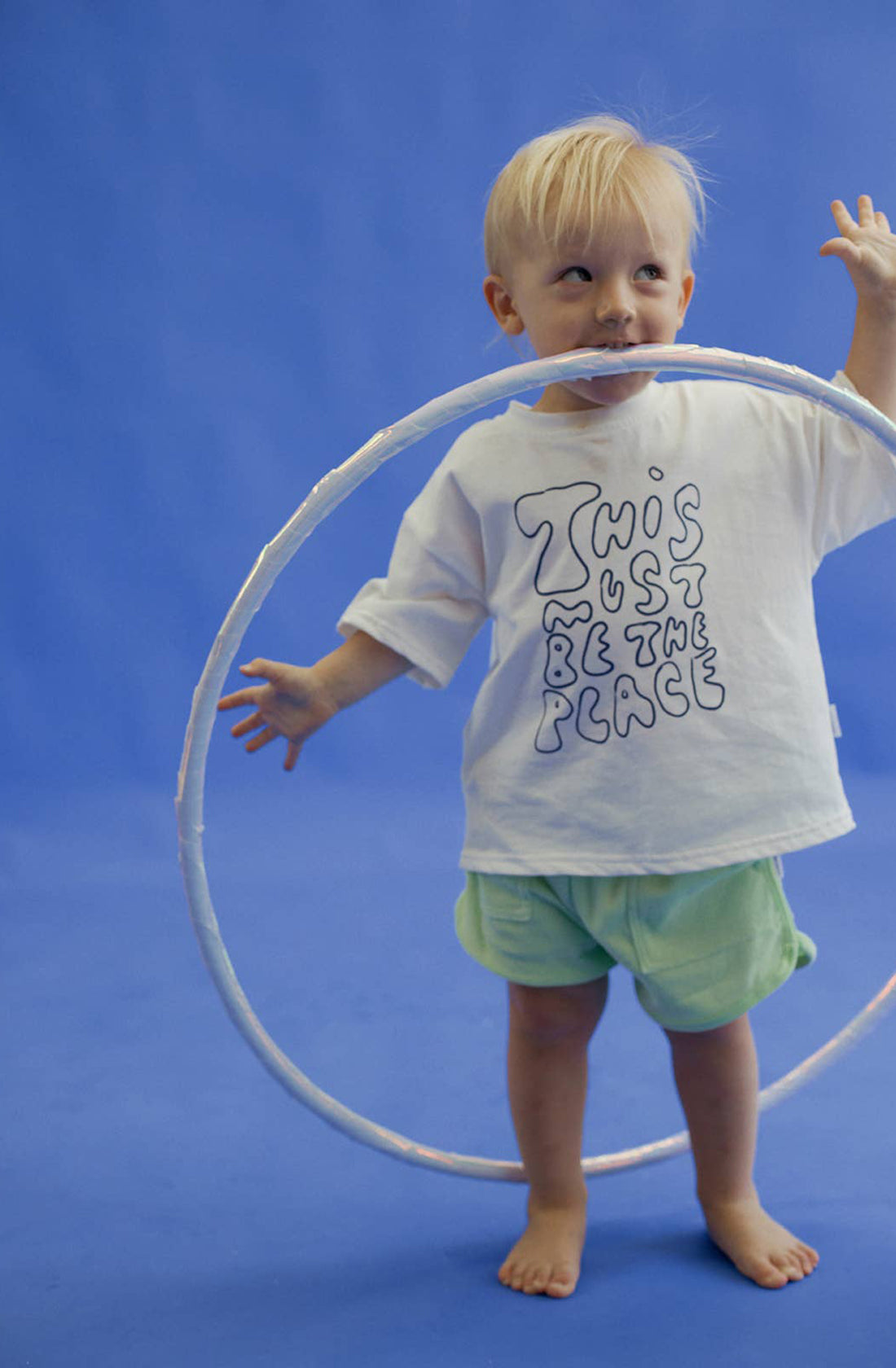 a little boy wearing the homey terry towelling shorts in green holding a hula hoop.