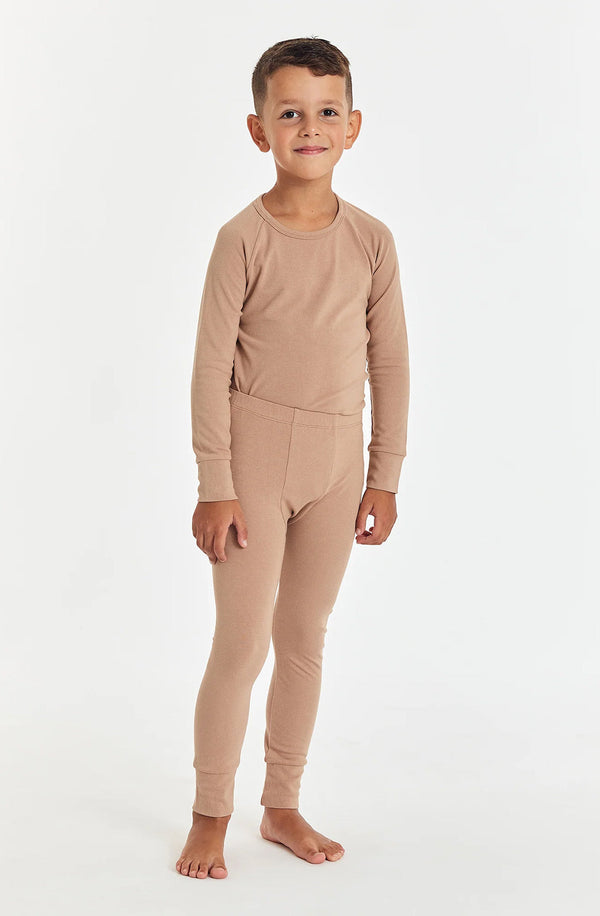 Boy standing against white background wearing the sleep set in tawny brown