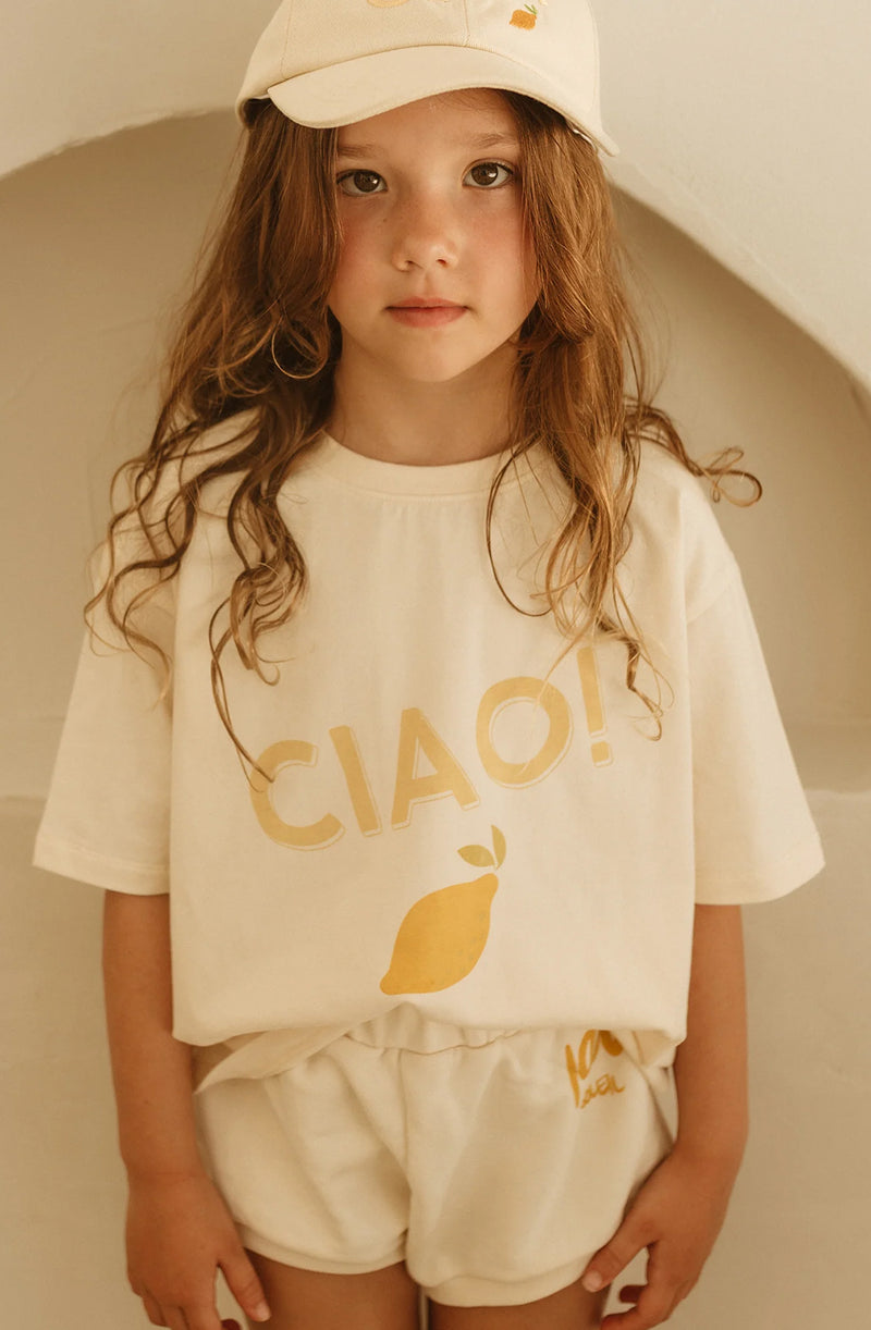 Girl wearing a baseball cap and the ciao print t-shirt tucked into shorts