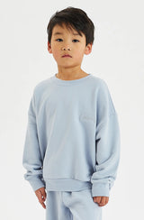 Boy wearing pale blue fleece top against a white background