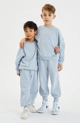 Two boys standing with arms around each other. Both are wearing pale blue fleece sets