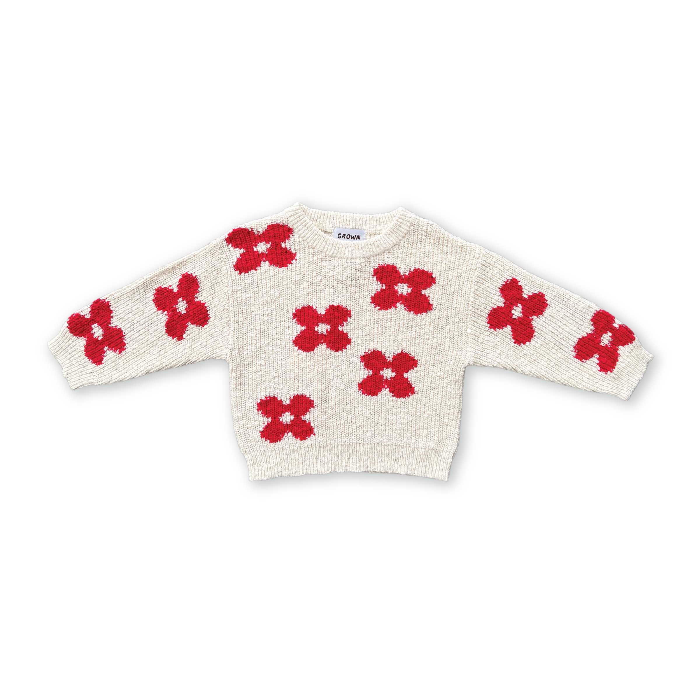 The GROWN Knitted Posy Pull Over is a cream-colored, organic cotton sweater with red posy flower patterns on the front, sleeves, and shoulders, shown against a black background.