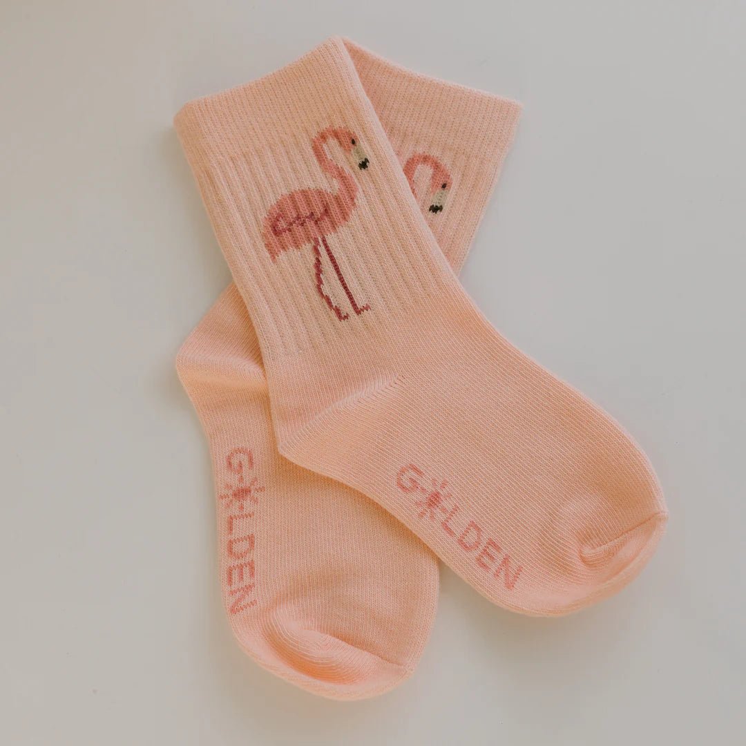 Flamingo Socks Sunset Pink by GOLDEN CHILDREN are a charming pair of children's ribbed socks in pink, showcasing a small flamingo design near the top. Each sock features "GOLDEN" written in pink on the foot and comes with reinforced toe caps for added durability. The socks are displayed flat on a white surface.