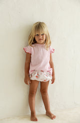 Girl standing against white background with Penny blouse tucked into Vali bloomers