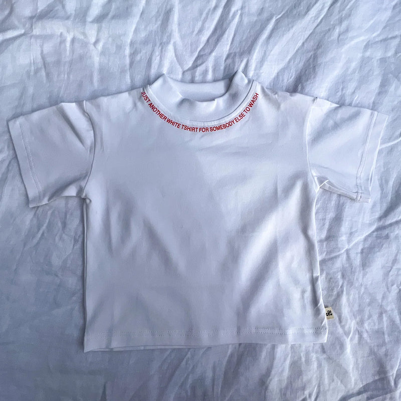 Flat lay of Just Another Tee in red on a white fabric background
