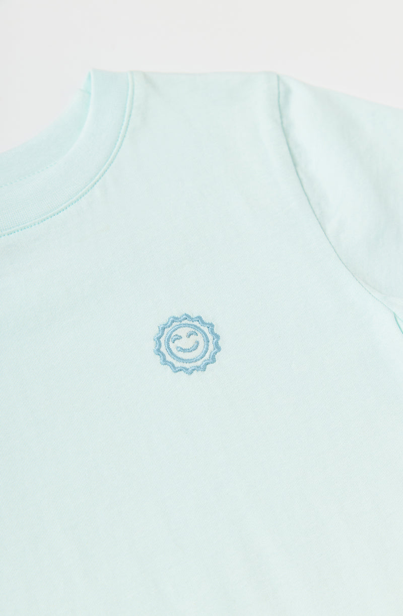Close up of embroider smiling sun on the chest of Rainbow Days tee