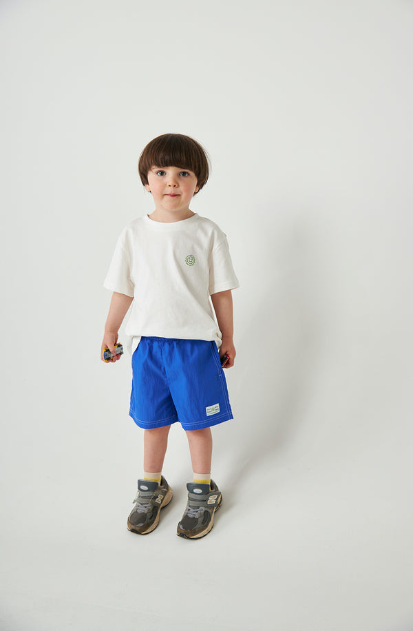 Boy standing in front of white background wearing the Runner short with a white t-shirt