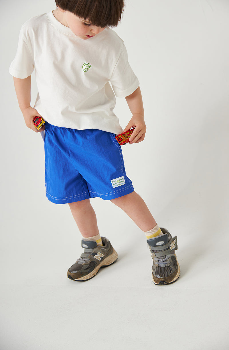 Boy wearing runner shorts, putting toy cars in his pocket