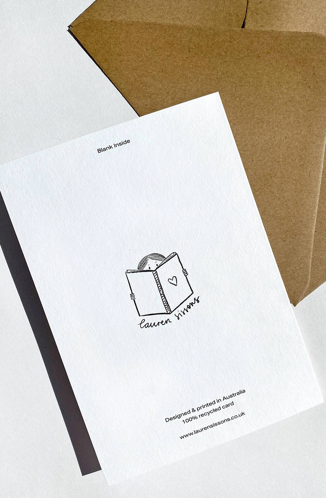 Greeting card on a white surface next to a brown envelope. The card features a minimalistic sketch of mushrooms and the text reads, "Welcome Little One," designed by LAUREN SISSONS STUDIO. Printed on recycled paper in Australia, it makes for a gender-neutral baby greeting card.