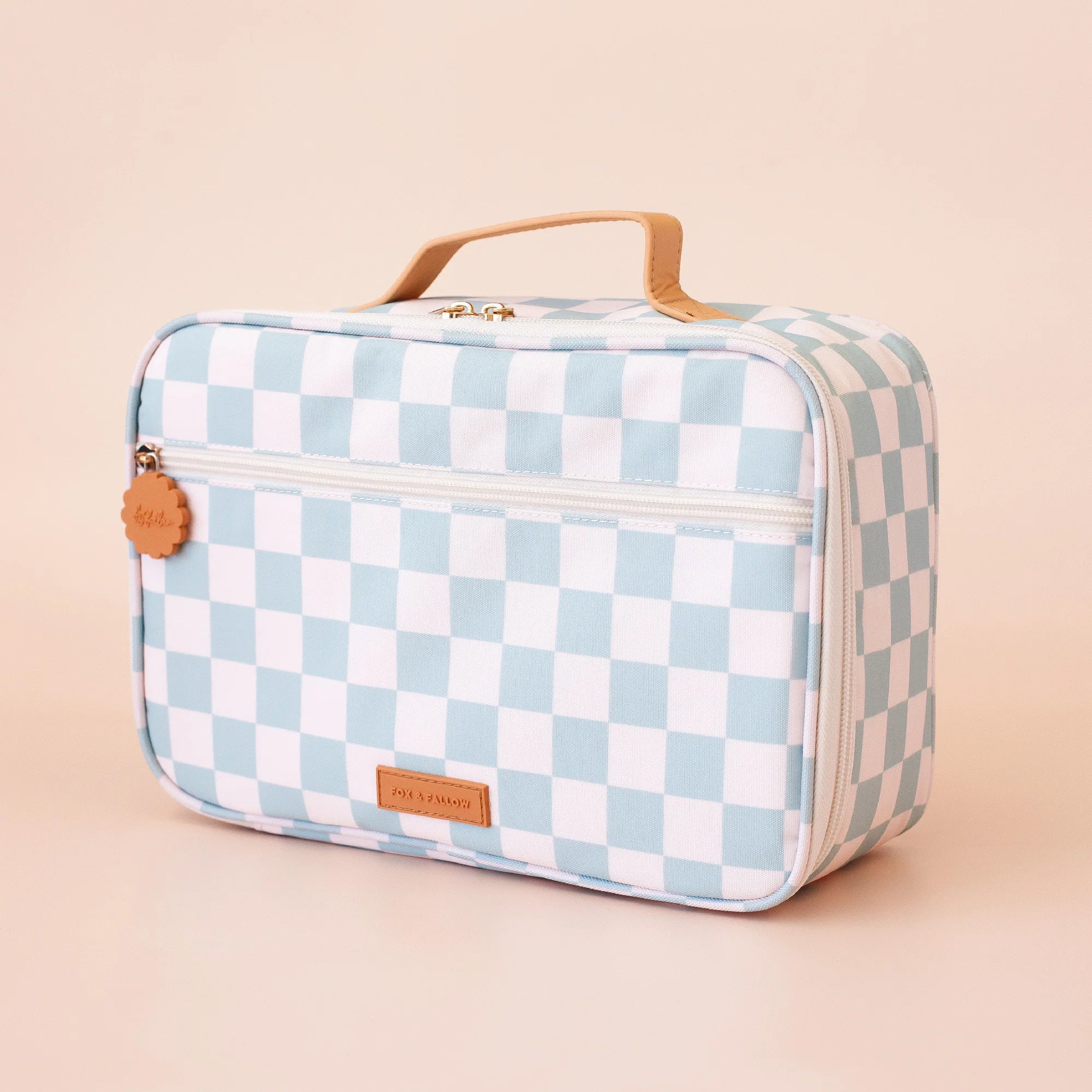 The FOX & FALLOW Sage Check Large Lunch Bag is a rectangular, light blue and white checkered insulated bag with a tan handle, zippered front pocket, brown label at the bottom center, and is shown against a beige background.