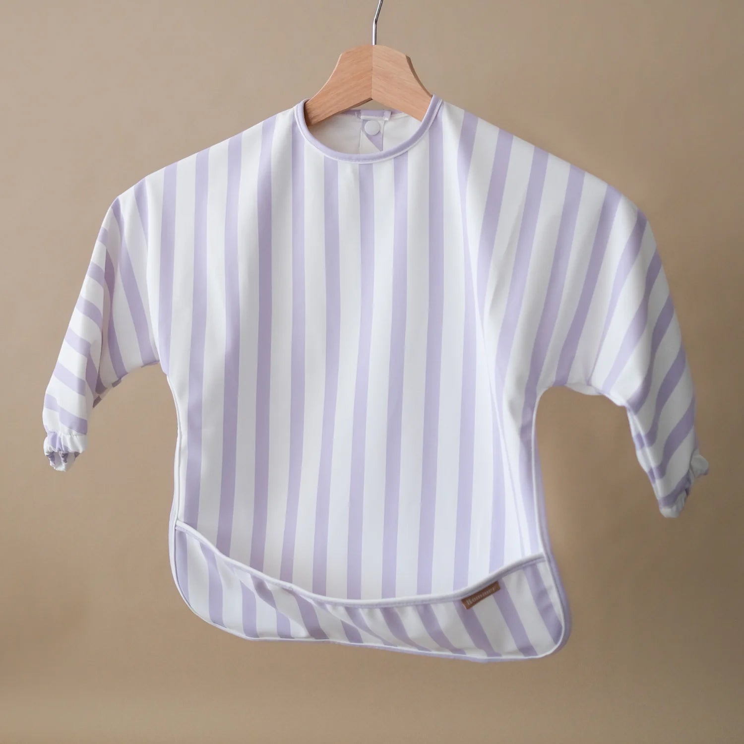 ROMMER Smock Bib in Lilac Stripe hanging from a coat hanger.